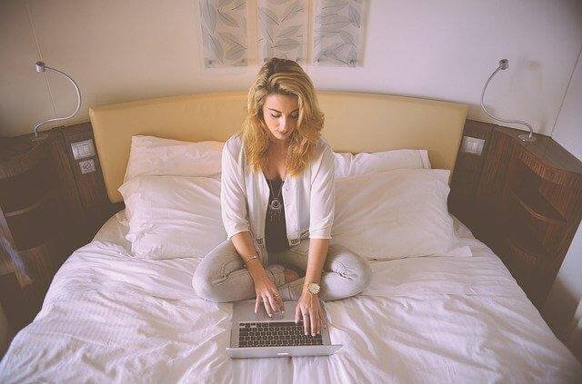 A person sitting on a bed with a computer

Description automatically generated with medium confidence